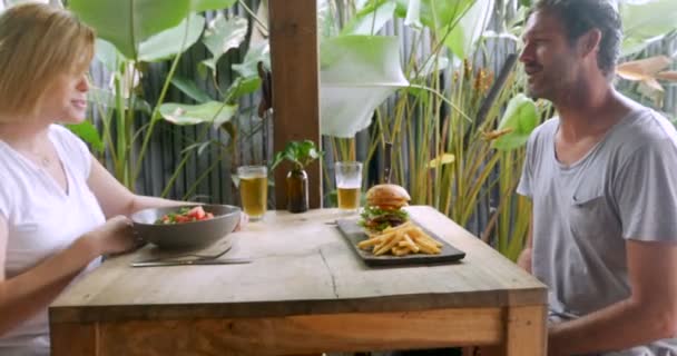 Empuje de una atractiva pareja celebrando con una cerveza fría y una comida — Vídeos de Stock