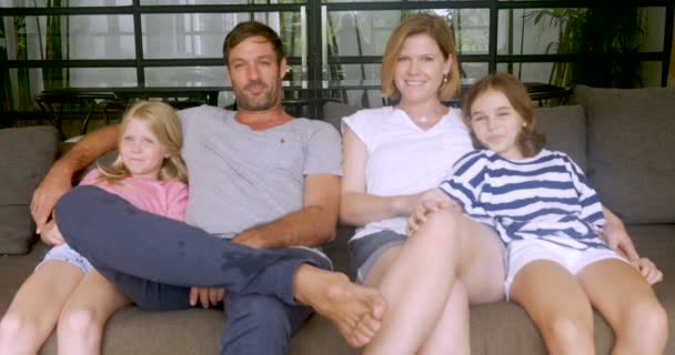 Ευτυχισμένη οικογένεια κάθεται σε έναν καναπέ μαζί χαμογελώντας και δίνοντας τους αντίχειρες — Αρχείο Βίντεο