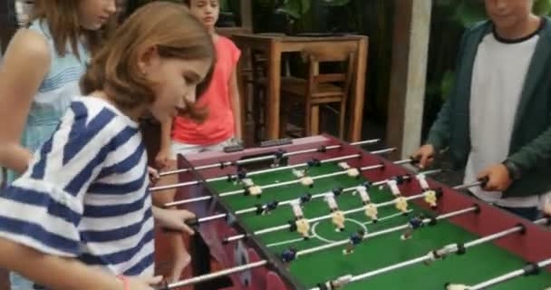 Dos chicas jóvenes anotando un gol contra dos chicos jugando futbolín — Vídeo de stock