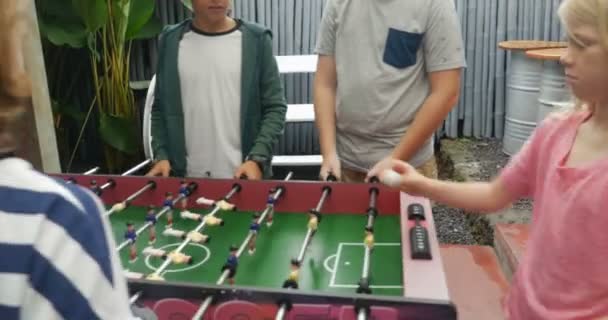 Group of young pre teen friends with both boys and girls playing foosball — Stock Video