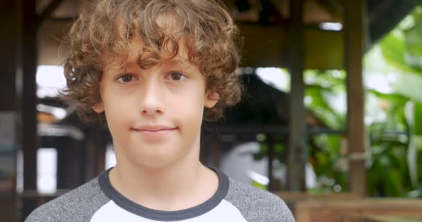 Portrait of a cute young 11 - 12 year old boy with curly hair smiling — Stock Video