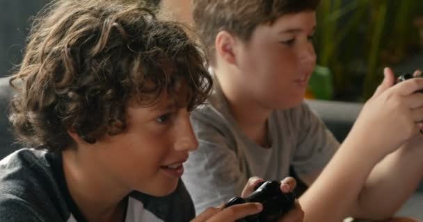 Закрытие двух мальчиков в возрасте от 11 до 13 лет, играющих в видеоигры с ручными контроллерами — стоковое видео