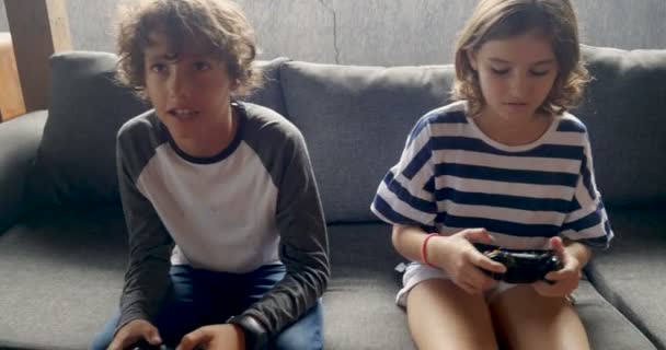 Fiatal 11-12 év régi fiú és lány játék video játékok, a kézi vezérlő — Stock videók