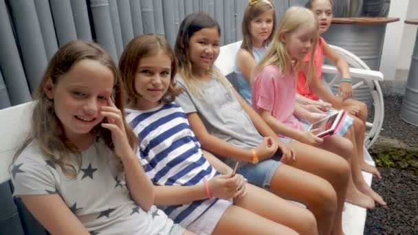 Разнообразная многонациональная группа молодых девушек, сидящих на скамейке — стоковое видео