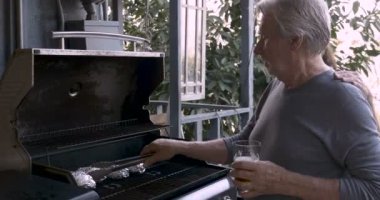 Bir Barbekü yemek yapıyor iken mutlu büyük oğlu yaşlı bir adam onun omzuna koyar