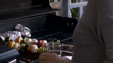 Onun 70 li yıllarda sağlıklı sebzeli şiş kebap üzerinde sıcak bir Barbekü yerleştirerek kıdemli yaşlı adam