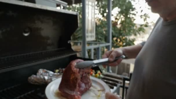 Hombre mayor colocando un filete rojo en una parrilla de barbacoa caliente con brochetas de verduras — Vídeo de stock