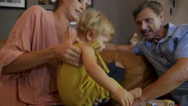 En mamma håller dottern baby medan Fadern spelas med block — Stockvideo