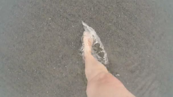 POV of a woman walking through the shallow water as a small wave comes in — Stock Video