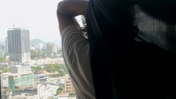 Empresario preparándose para su día mirando por una ventana a una ciudad moderna — Vídeo de stock