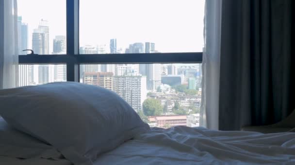 Tilt down of a bed with pillows and a modern city with tall buildings — Stock Video