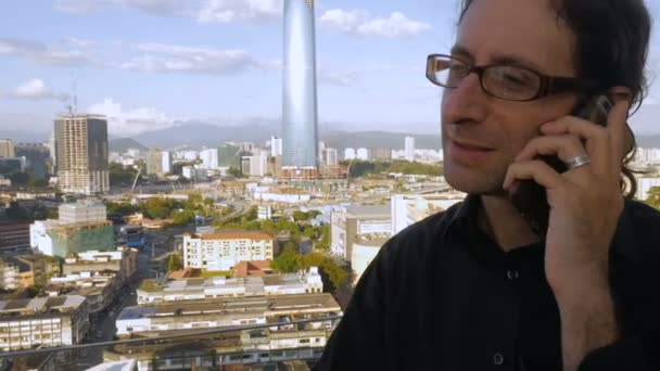 Homme parlant sur son téléphone portable à l'extérieur hochant la tête oui avec toile de fond de la ville — Video