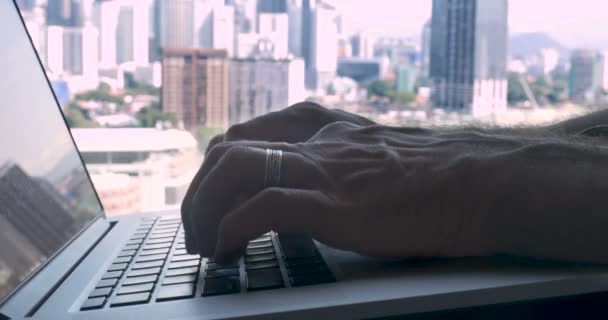 Вытолкнуть из рук человека, печатая на клавиатуре Qwerty ноутбука с видом на город — стоковое видео