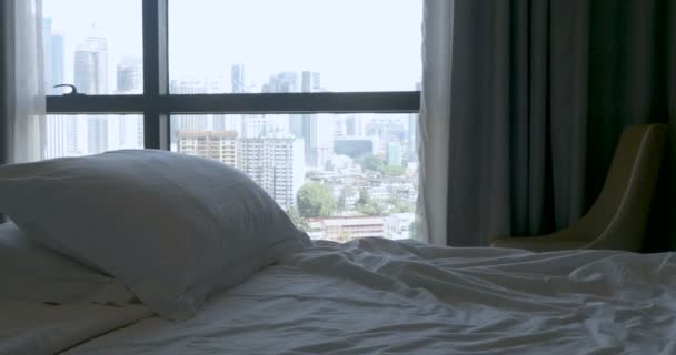 Inclinado hacia arriba de una cama vacía con dos almohadas y una gran vista de la ciudad — Vídeos de Stock