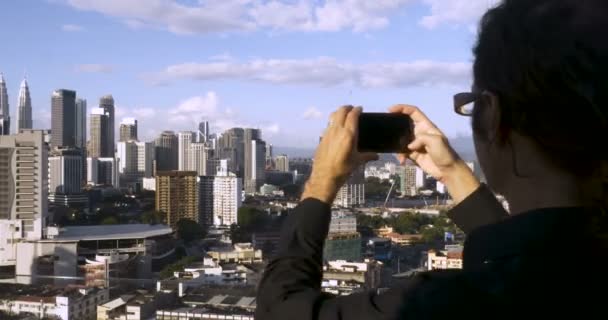 Τουριστική λαμβάνοντας Πόλη Δείτε φωτογραφίες των δίδυμων πύργων Petronas με το κινητό του — Αρχείο Βίντεο