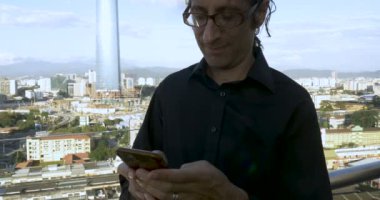 Adam akıllı telefonundan mesaj göndermek bir çatıda dışında ayakta