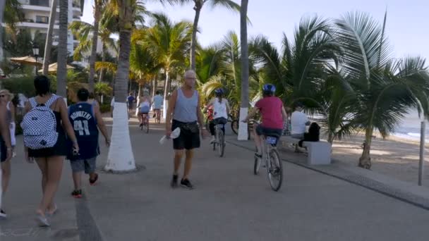 Urlauber zu Fuß und mit dem Fahrrad auf dem malecon in puerto vallarta — Stockvideo