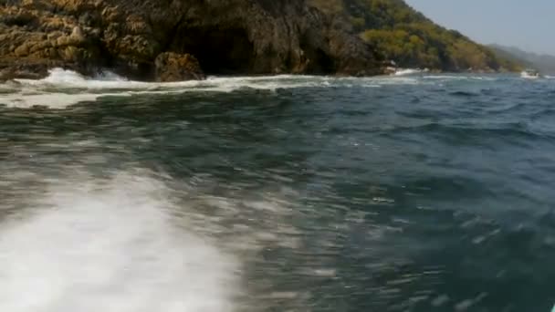 Vatten krascha längs kanten på en båt resor nära en bergig strandlinjen — Stockvideo
