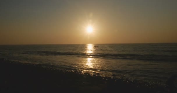 Kleine boot oversteekt de reflectie van de ondergaande zon in de Oceaan bij zonsondergang — Stockvideo