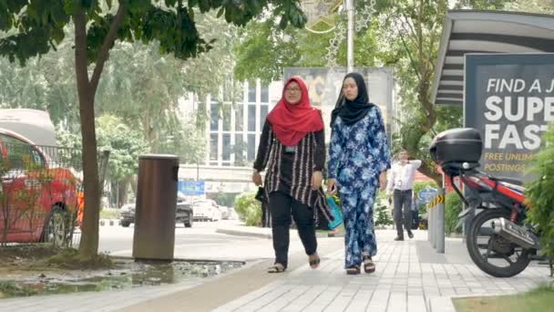 Dos mujeres musulmanas en burqas caminando en una acera en Kuala Lumpur, Malasia — Vídeo de stock