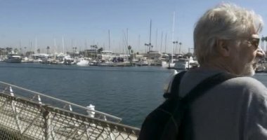 Yakışıklı sağlıklı komuta sizde bir Marinada bakan bir çit karşı yaslanmış
