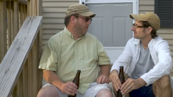Двоє друзів чоловічої статі розмовляють і обговорюють щось, тримаючи напої — стокове відео