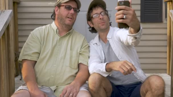Two male best friends taking a selfie photo sitting on porch steps — Stock Video