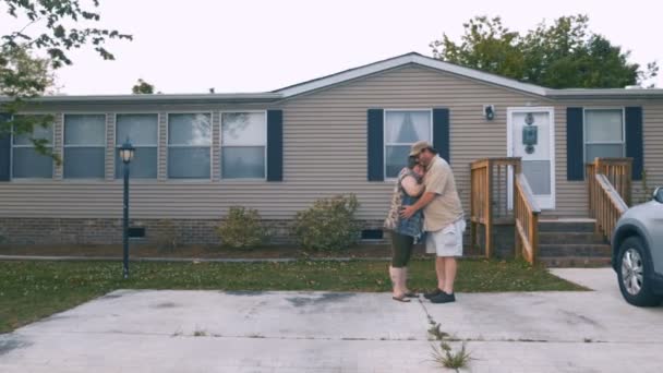 Feliz casal pesado abraçando na frente de uma casa fabricada — Vídeo de Stock