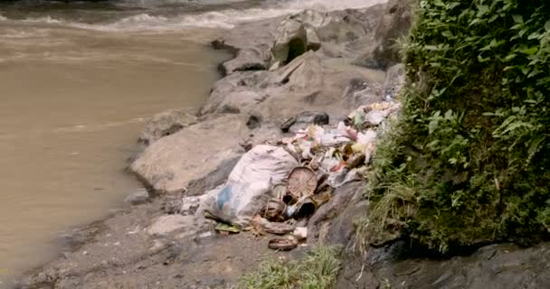 Piles d'ordures jetées au bord d'une rivière avec des offrandes à Bali — Video