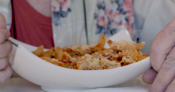 Senior man genieten van een mondvol van penne pasta met tomatensaus in café — Stockvideo