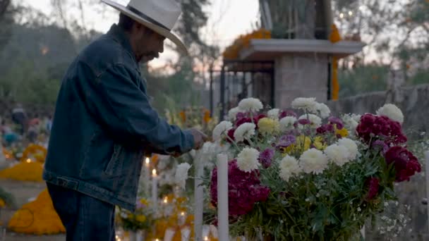 Мексиканські старий у ковбойському капелюсі запалювати свічки протягом дня мертвих — стокове відео