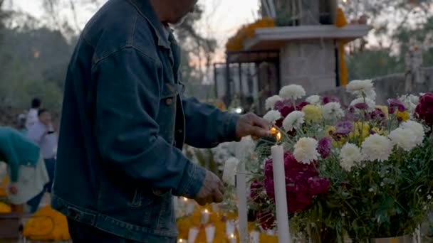 Mensen groeten elkaar terwijl een man licht kaarsen tijdens dag van de doden — Stockvideo