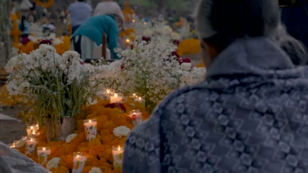 Dolly shot of people sitting at a graveyard during day of the dead — Stock Video