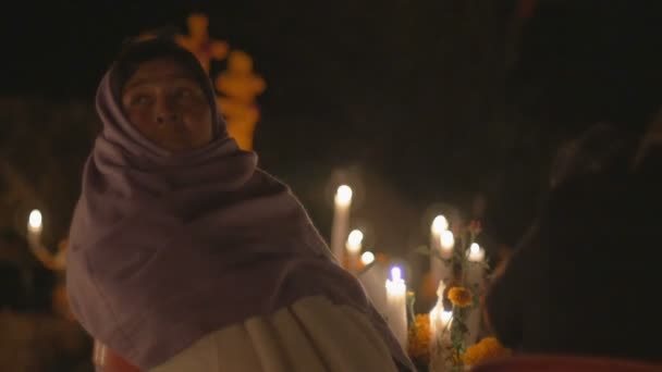 Woman wearing a scarf over her head sitting by candles during day of the dead — Stock Video