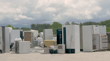 Kırık bir dehumidifier atılan mutfak aletleri yığınına taşıyan adam