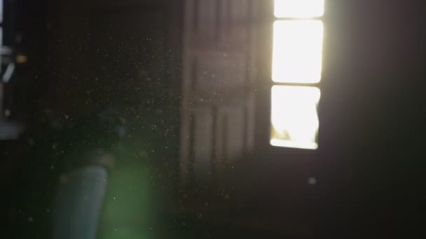 Poeira flutuando no ar de uma sala escura com uma janela aberta e sol — Vídeo de Stock