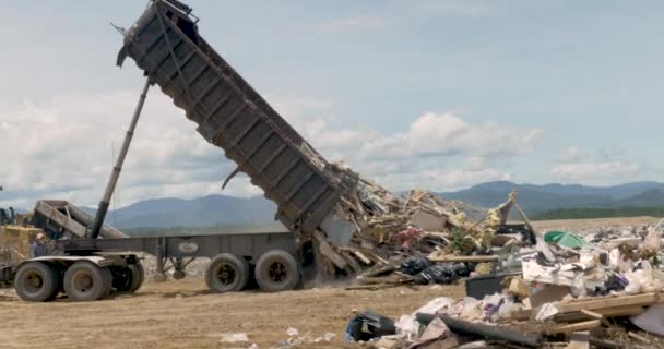 Grande caminhão de despejo esvaziando um lixão de lixo de construção em um aterro — Vídeo de Stock