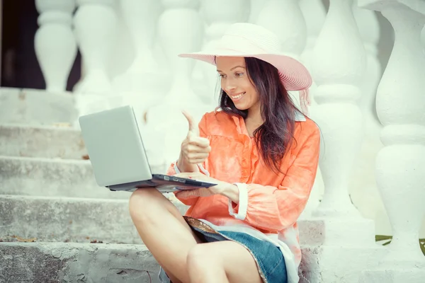 Attraente giovane donna utilizzando il computer portatile seduto su una scala di legno — Foto Stock