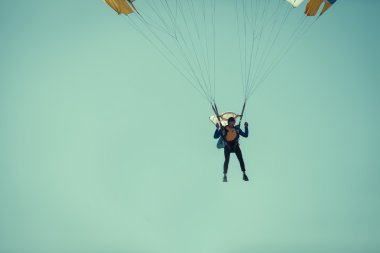 Skydiver güneşli açık gök renkli paraşüt üzerinde.