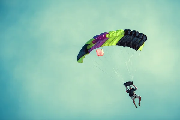 Skydiver güneşli açık gök renkli paraşüt üzerinde.