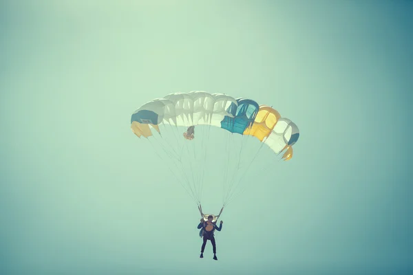 跳伞运动员在彩色降落伞在阳光明媚的晴空. — 图库照片