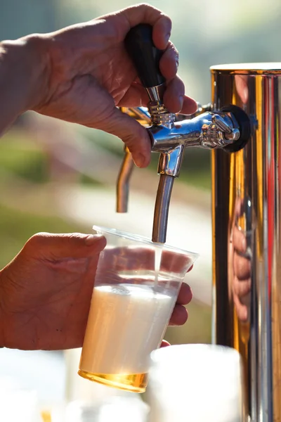 Barman hand at beer tap pouring a draught lager beer — Stock Photo, Image