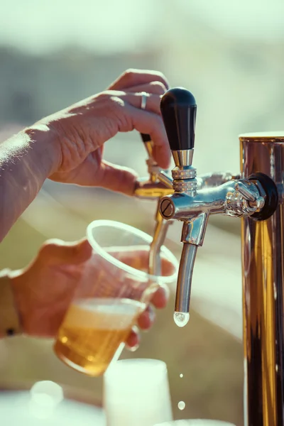 barman hand at beer tap pouring a draught lager beer