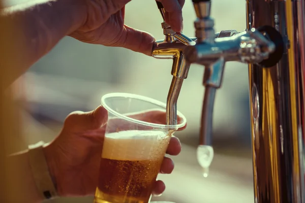 Mão barman em torneira de cerveja derramando uma cerveja lager calado — Fotografia de Stock