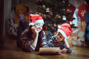Genç anne ve oğlu tarafından sıcak bir şömine bir tablet PC'yi kullanma 