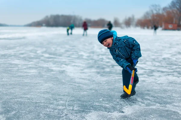 Un enfant avec un bâton sur la glace patiner en hiver marche sur t — Photo