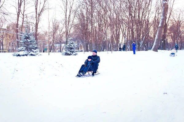 Jovem família correndo através da neve com trenó — Fotografia de Stock