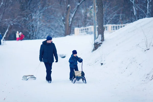 Giovane famiglia correre attraverso la neve con slitta — Foto Stock