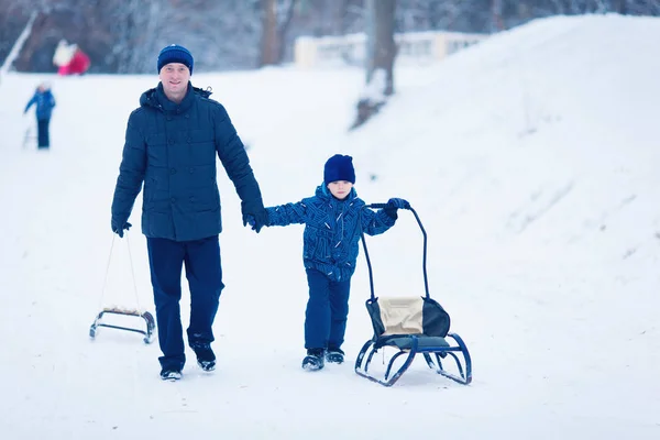 Jovem família correndo através da neve com trenó — Fotografia de Stock