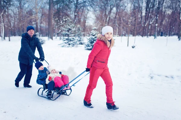 Giovane famiglia correre attraverso la neve con slitta — Foto Stock